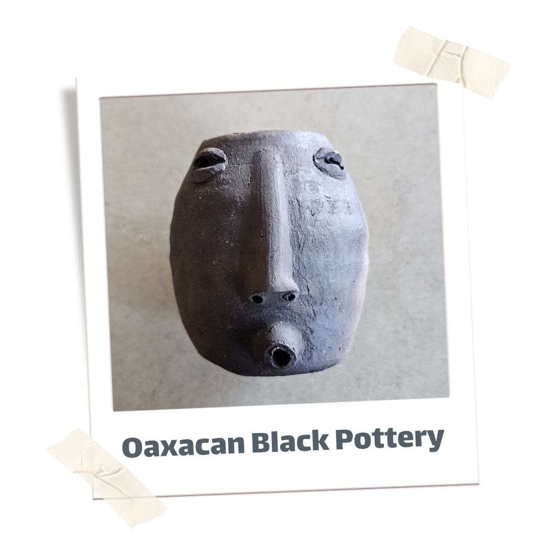 Small black pottery vase with a face