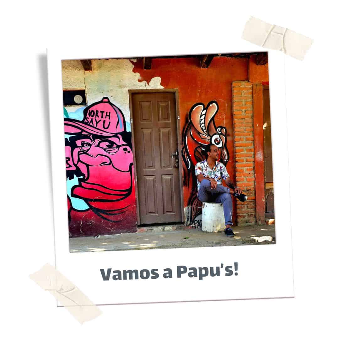 Man sitting on a bench with graffiti behind him smiling. 